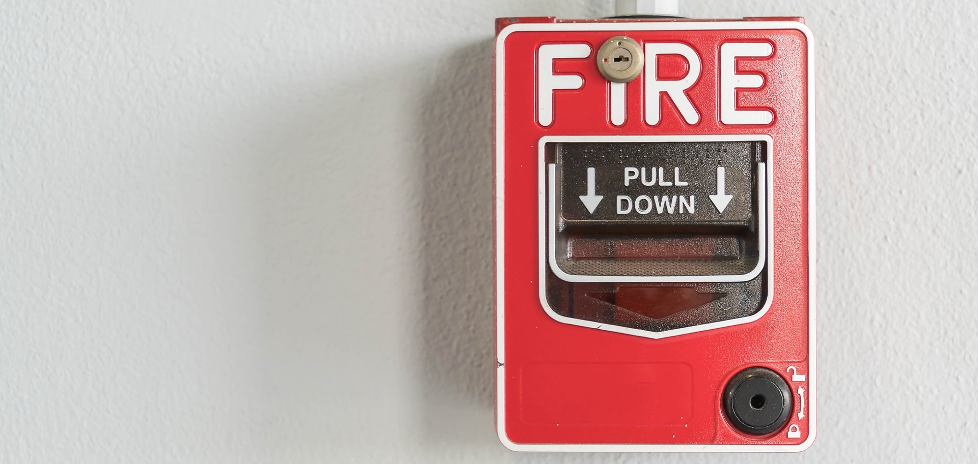 Red fire alarm pull station mounted on a commercial building wall
